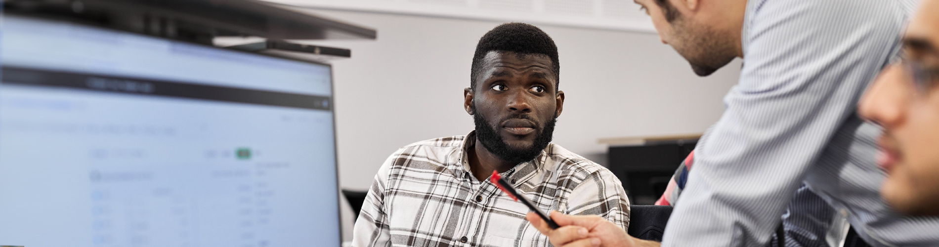 Student listening to lecturer at a set of computer terminals.