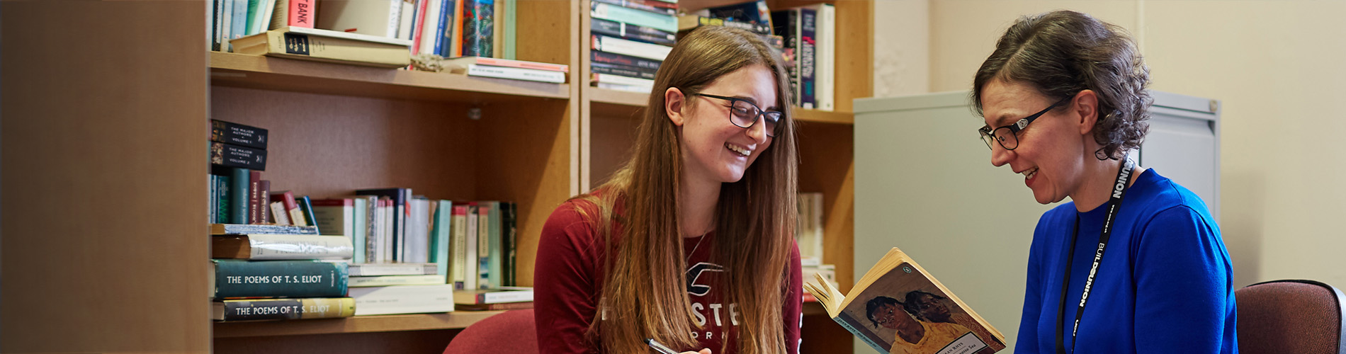 Lecturer holding a book and having a discussion with a student.