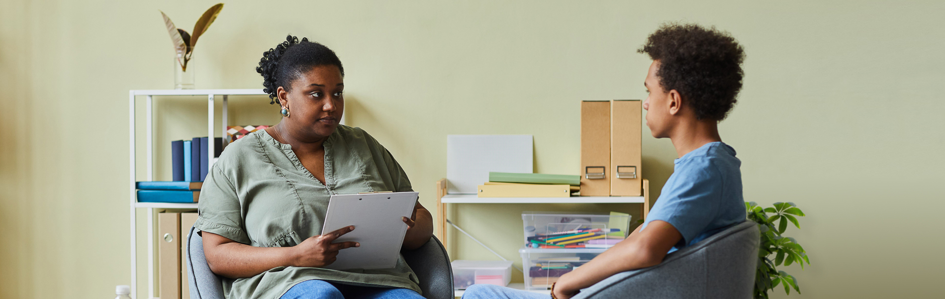 Social worker holding a clipboard and speaking with a client.