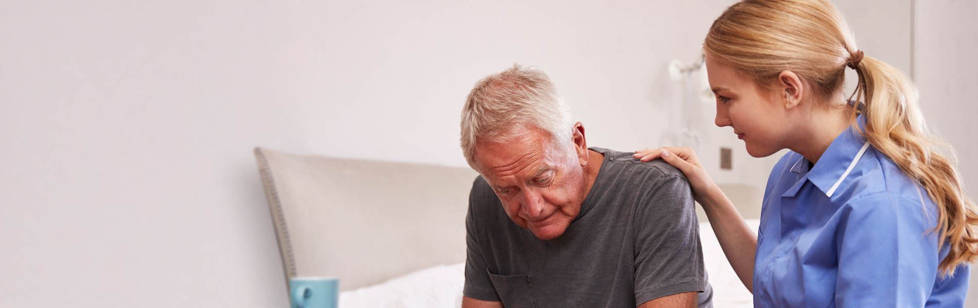 Female nurse consoling an elderly gentleman.