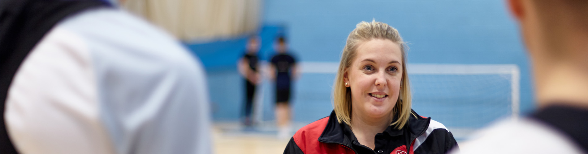 Lecturer teaching students in a sports gym.