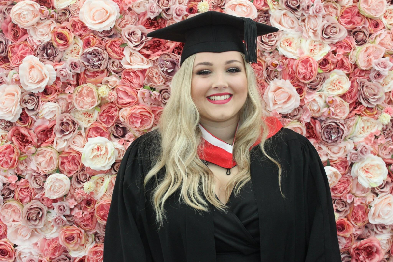 Evie Hudson grad pic flower wall.