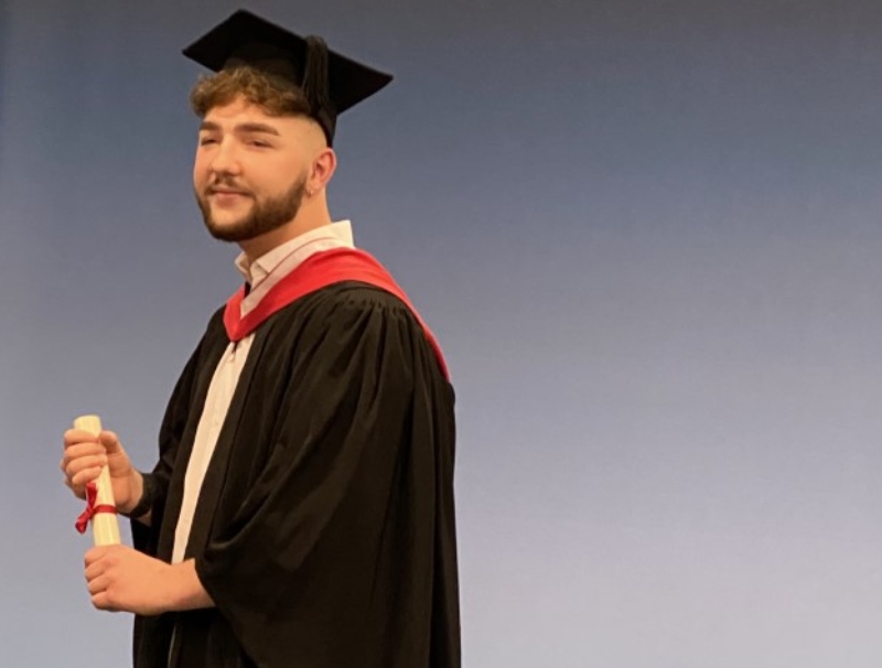 Tom Allen graduating in hall.