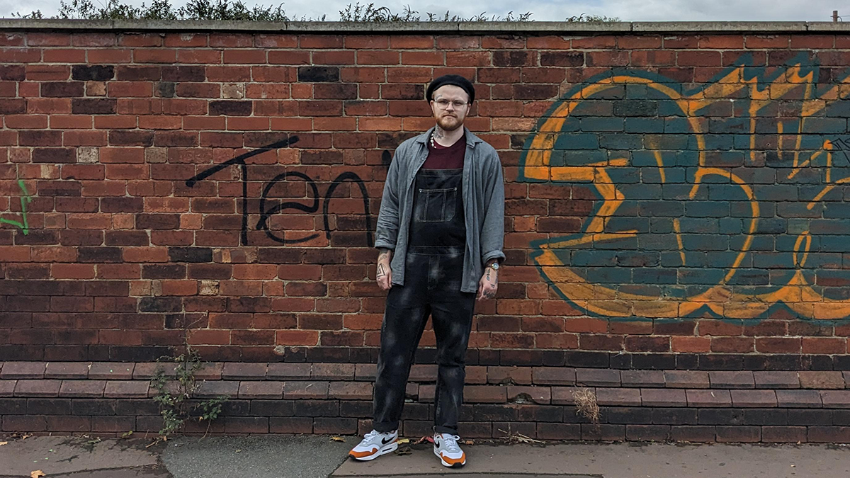 A student posing in front of a brick wall..