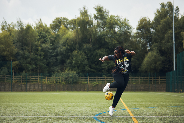 Female student performing a trick with a football on a 3G pitch..