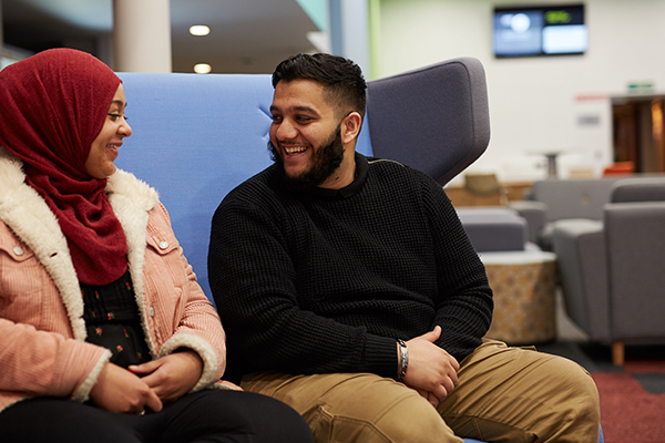 Two student socialising in fountains court social space.