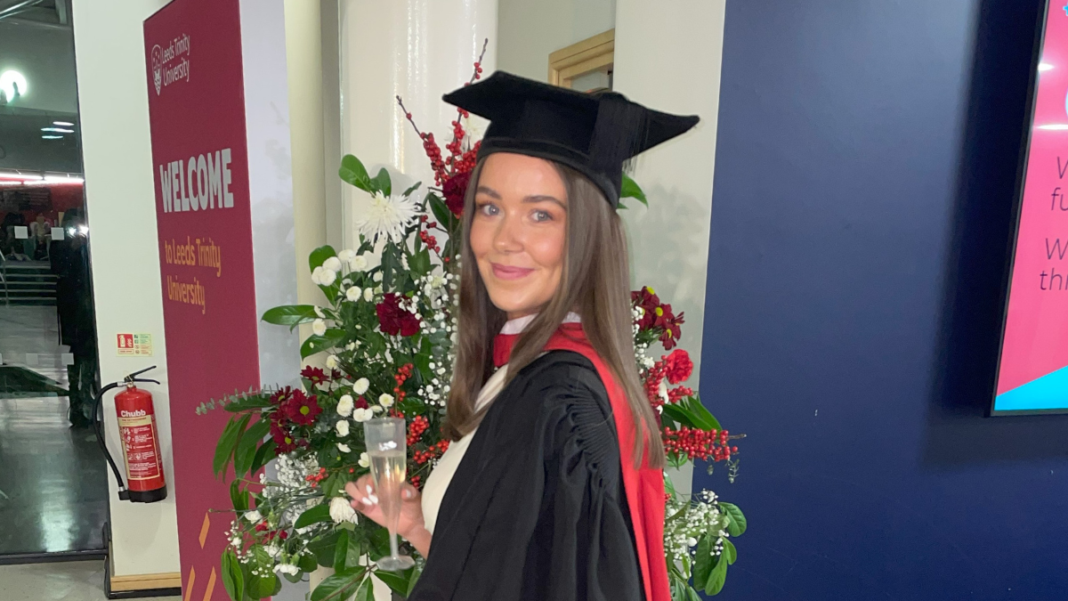 A student in graduation cap and gown smiling..