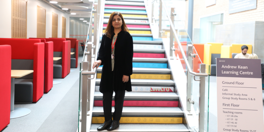 Trainee standing on steps in university library.