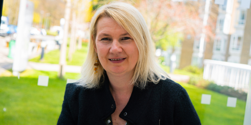 Female with blonde short hair smiles wearing black jacket.