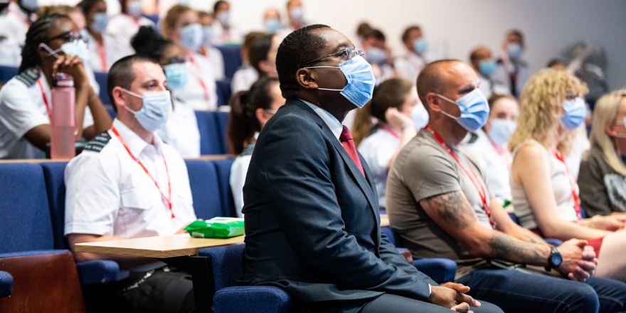 Side view of students in lecture theatre with face masks on, Leeds Trinity Vice Chancellor Charles Egbu sits in the foreground.