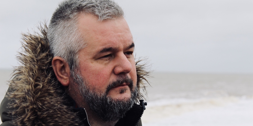 Man in black coat on beach.