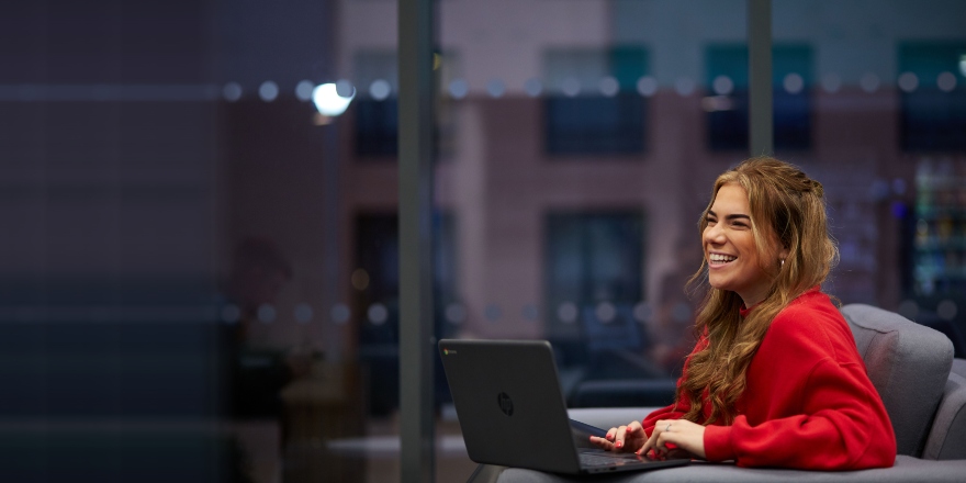 Female student in red jumper with laptop.