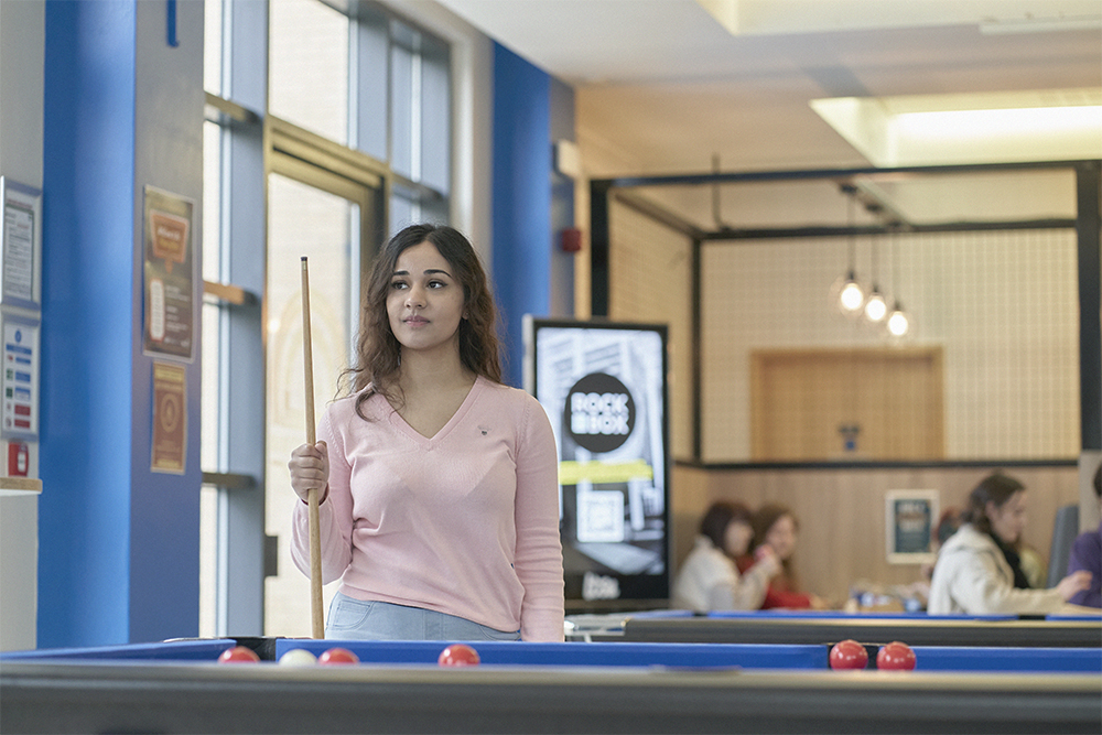 Student playing pool in student bar.