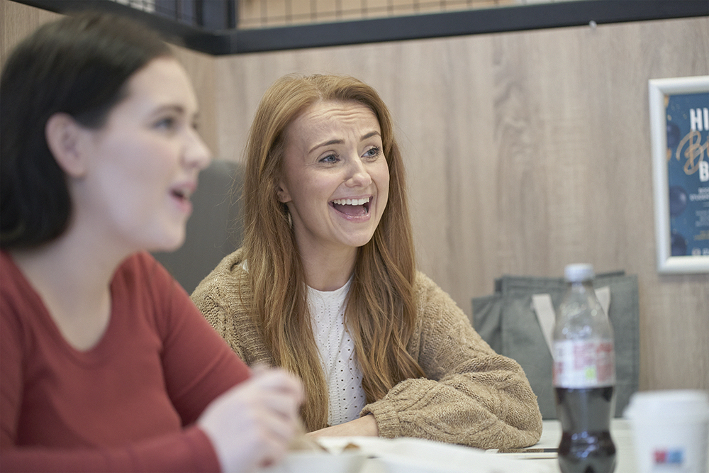 Two students sat at a table and talking in the student bar.