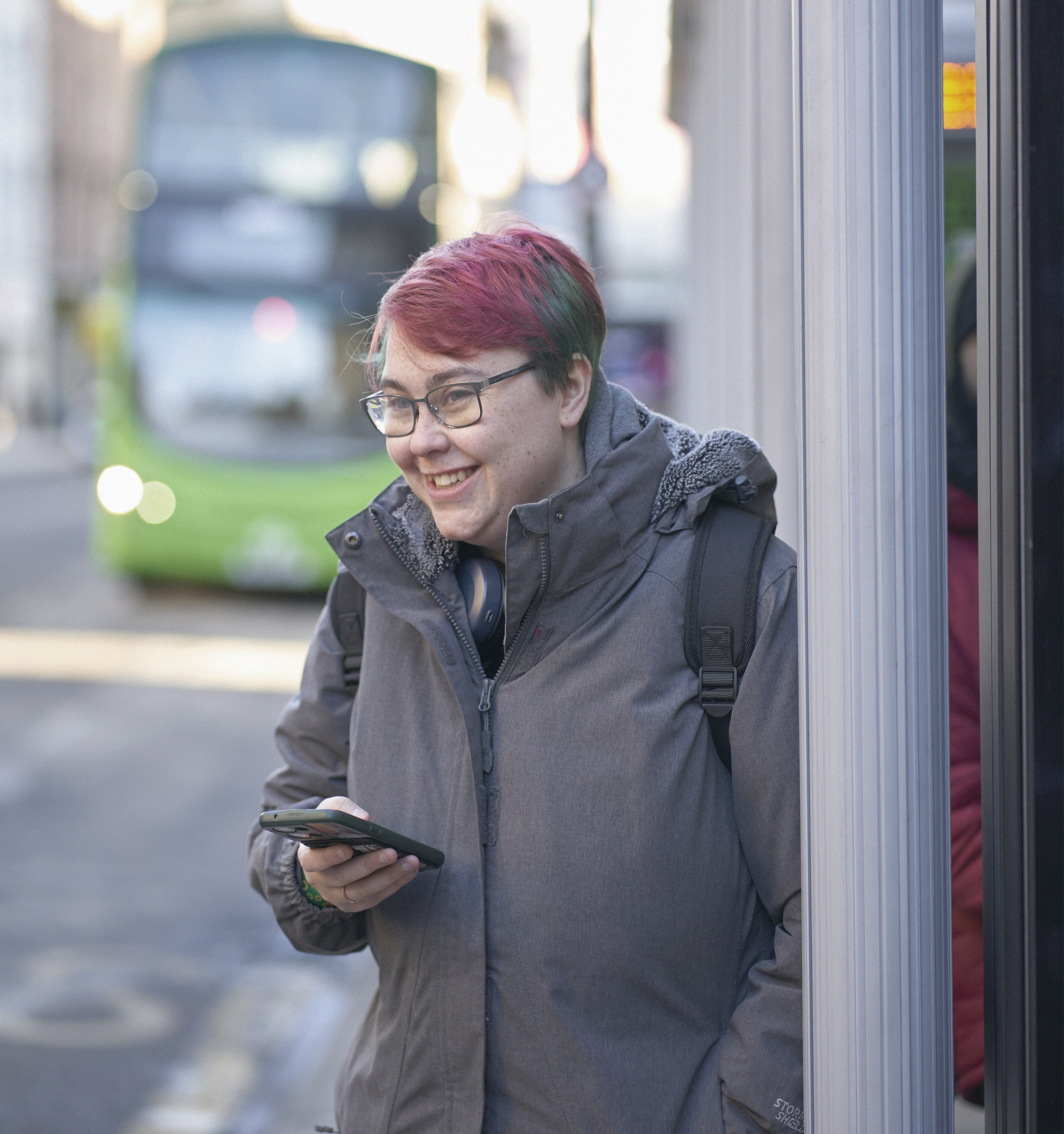 Student waits at bus stop in Leeds City Centre.