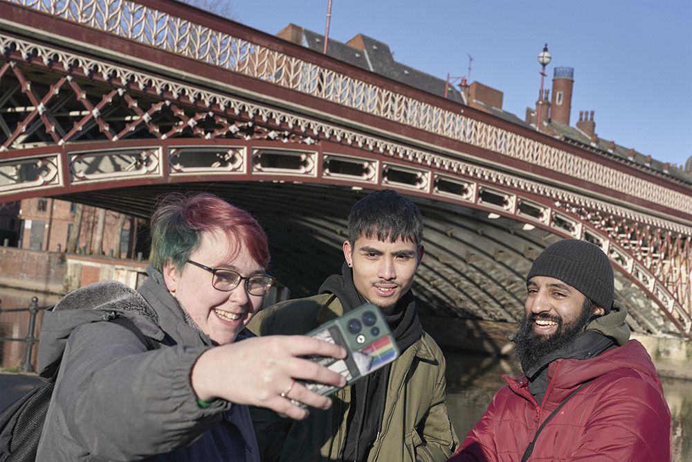 Three student pose for a selfie near Leeds bridge.