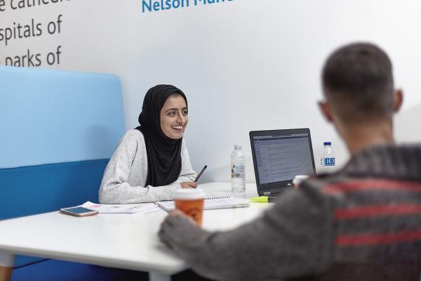 Students chatting around a table in the Andrew Kean Learning Centre..