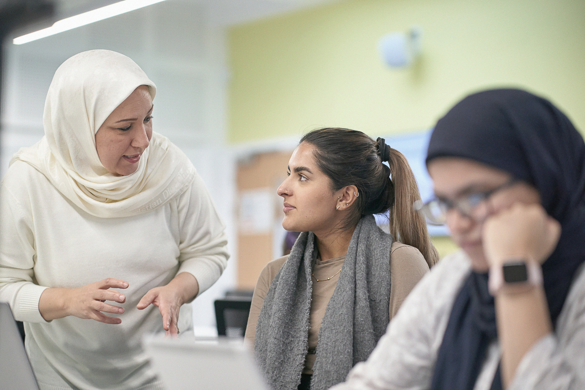 Student talking with lecturer in computer suite.