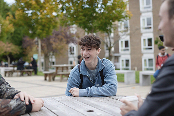 Student sits outside Main Campus on benches.