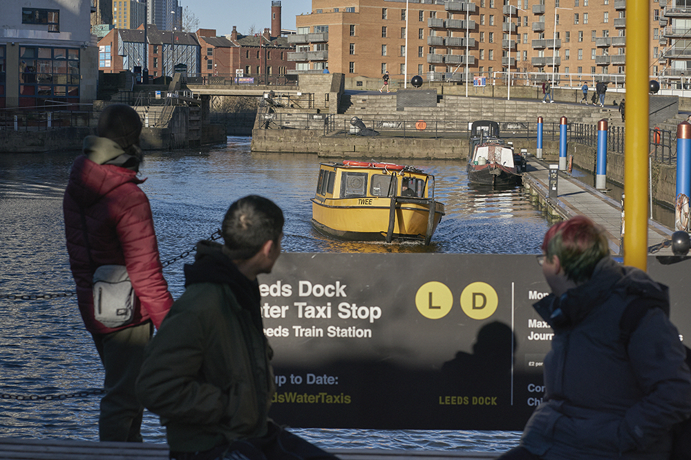 Three students waiting for the water taxi at Leeds Dock.