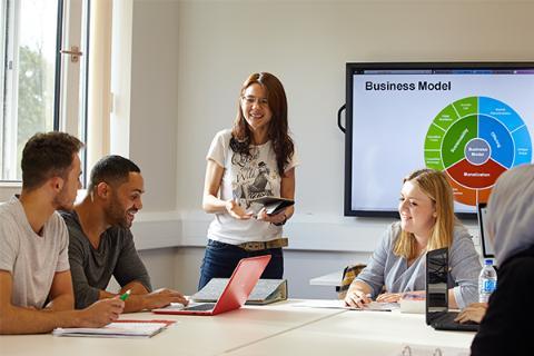 lecturer teaching to a room of students.